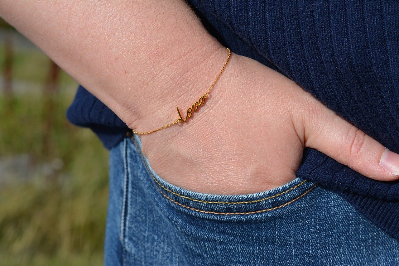 Dainty gold script bracelet on a wrist